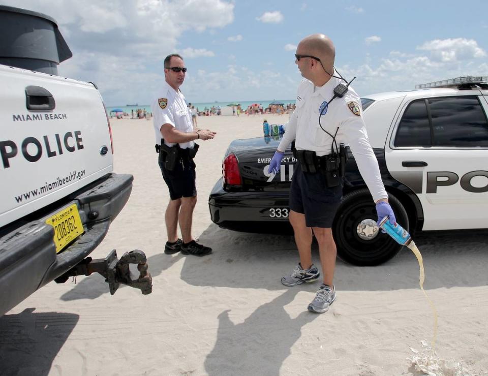 Officers C. Beck, left, and A. Soto empty out confiscated containers of alcohol at Miami Beach on Saturday, March 17, 2012. Miami Beach police were stationed at various beach entrances, checking people’s coolers and dumping out alcohol.