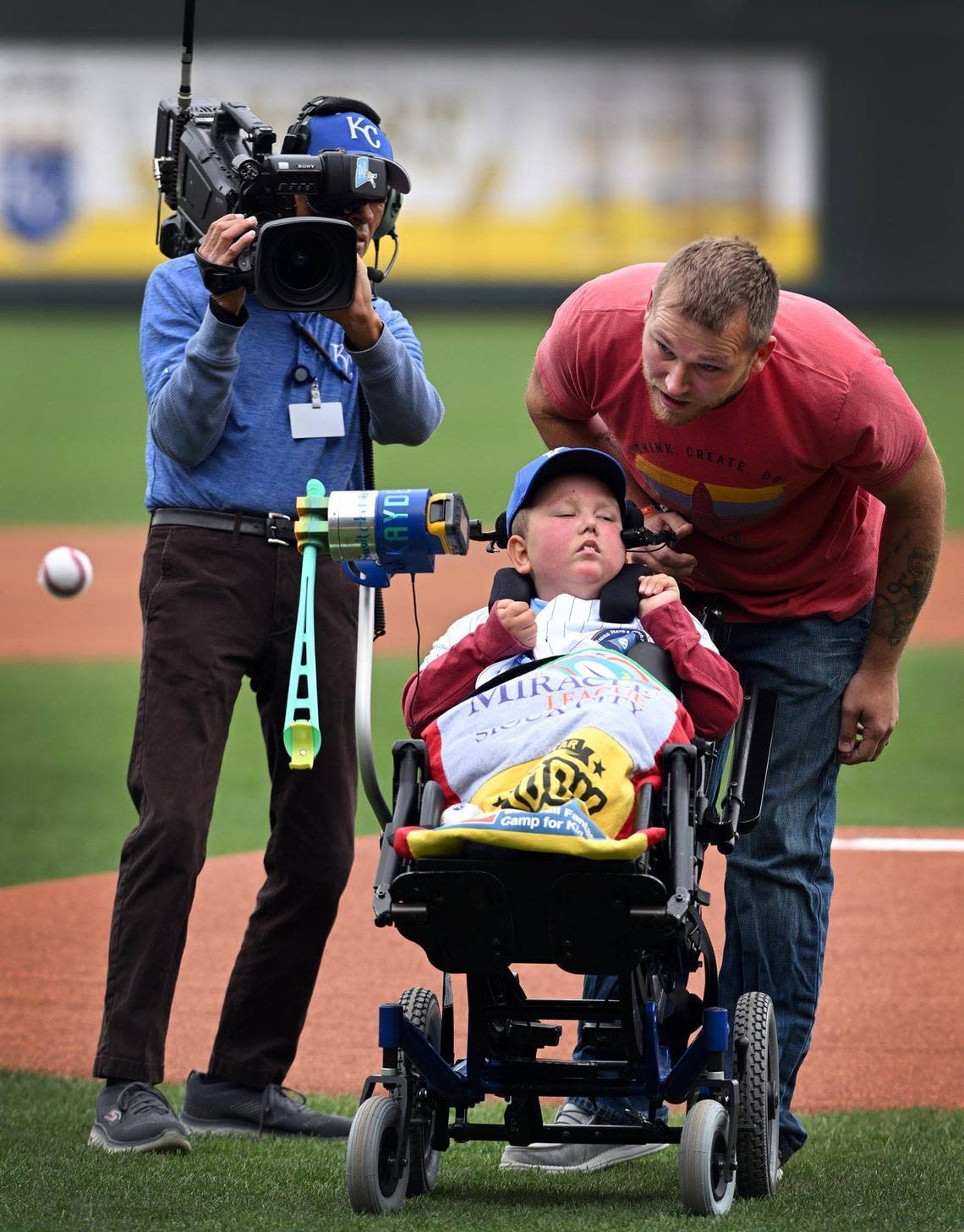 Kayden Rhoades was given 24 hours to live at birth, but 15 years later he threw out the first pitch on Thursday at Kauffman Stadium with the help of his family. Rhoades, who was born with hydranencephaly, used a device his father Dustin created for him to complete the feat. It was a bucket list day in every way for the family from Sioux City, Iowa.