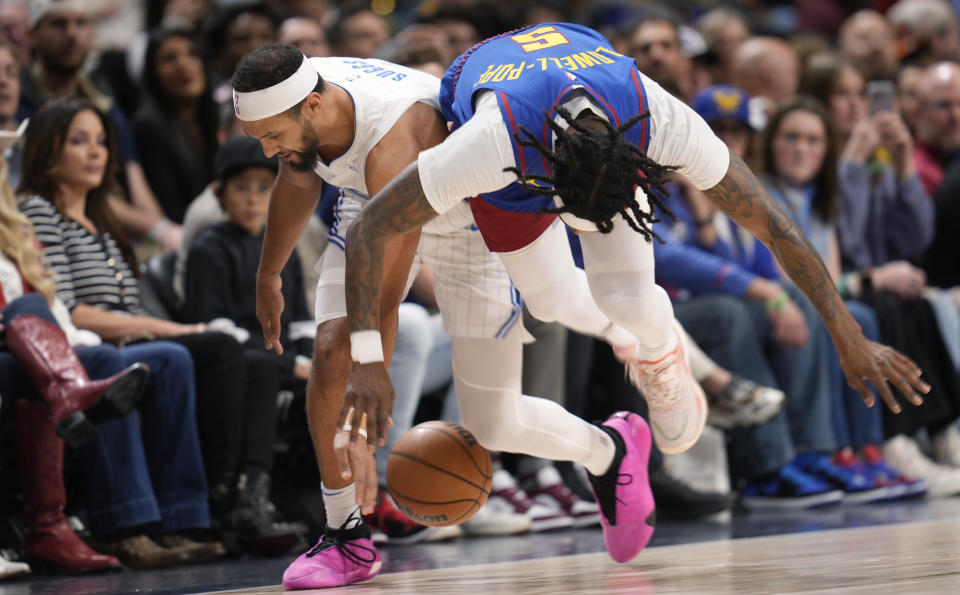 Orlando Magic guard Jalen Suggs, left, and Denver Nuggets guard Kentavious Caldwell-Pope, right, fight for control of the ball in the first half of an NBA basketball game Friday, Jan. 5, 2024, in Denver. (AP Photo/David Zalubowski)