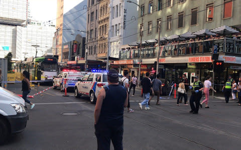 Pedestrians walk past as police and emergency services attend the scene of an incident involving a vehicle and pedestrians in Melbourne - Credit: Kaitlyn Offer/AAP via AP
