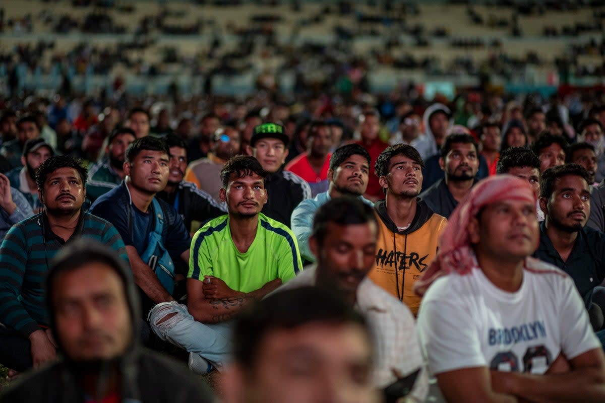 Trabajadores migrantes ven la Copa del Mundo en el área de aficionados de la zona industrial de entrada libre en Doha (EPA)