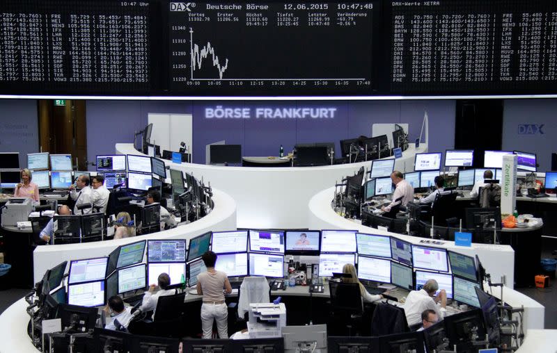 FILE PHOTO: Traders are pictured at their desks in front of the DAX board at the Frankfurt stock exchange