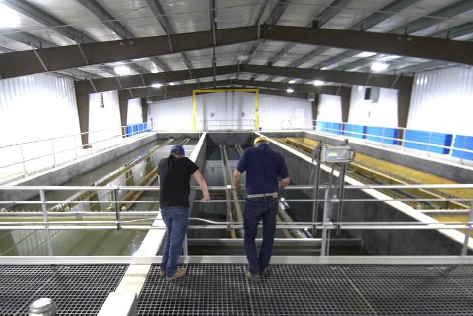 Dave Hoffman, left, and Paul Ziemkiewicz of West Virginia University's Water Research Institute check on clarifying pools at a facility they run where rare earth minerals are separated from acidic groundwater draining from an abandoned coal mine, June 25, 2024, in Mount Storm, W.Va. Researchers found that groundwater pouring out of this and other abandoned coal mines contains the rare earth elements and other valuable metals that are vital to making everything from electric vehicle motors to rechargeable batteries to fighter jets smaller, lighter or more powerful. (AP Photo/Marc Levy)