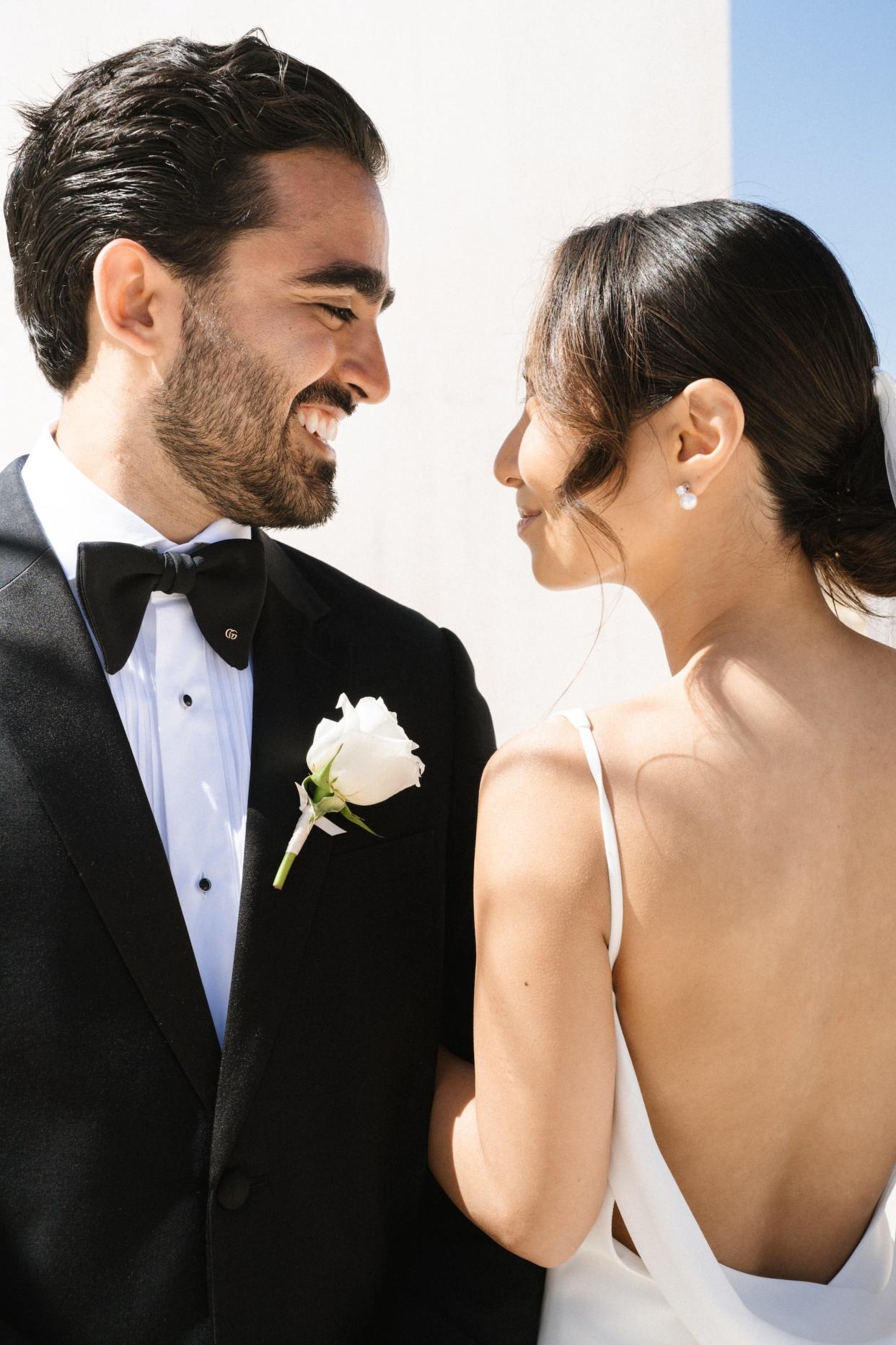 A bride and groom smile at each other in a close up shot.