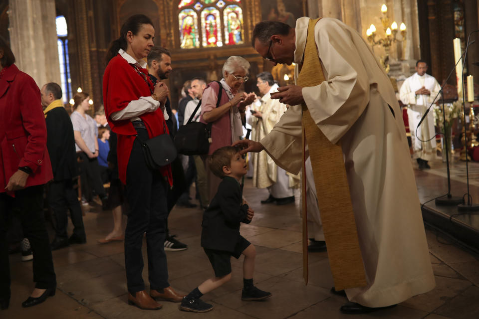 Priests give communion to faithfuls during a Sunday's Mass at the grandiose Saint-Eustache church on the Right Bank of the Seine river in Paris, Sunday, April 21, 2019. The archbishop of Paris and Catholics from around France and the world honored the firefighters who saved Notre Dame Cathedral, praying Sunday at a special Easter Mass for a swift reconstruction of the beloved monument. (AP Photo/Francisco Seco)