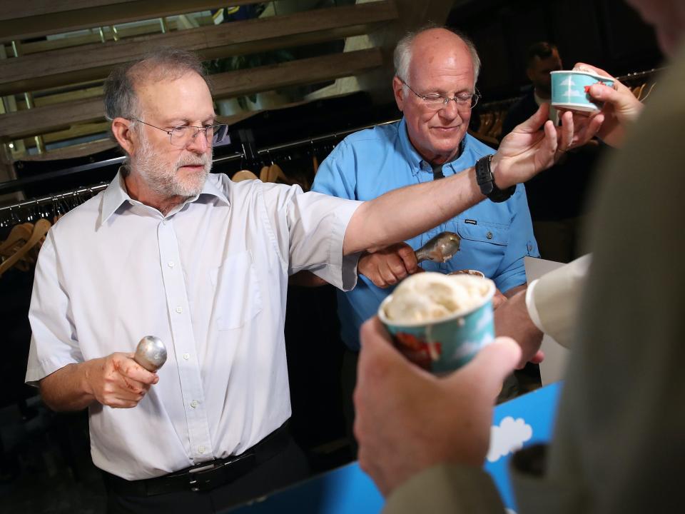 Ben & Jerry's co-founders Ben Cohen (R) and Jerry Greenfield (L) serve ice cream following a press conference announcing a new flavor, Justice Remix'd.