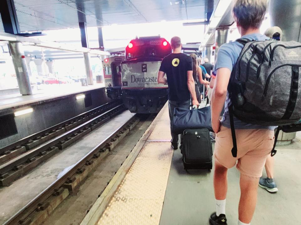 People with backpacks and suitcases walking toward Amtrak train