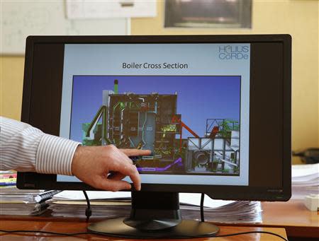 A worker points to a screen showing a biomass boiler diagram at the Helius Corde biomass energy plant in Rothes, Scotland March 20, 2014. REUTERS/Russell Cheyne