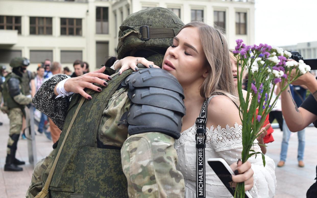 A woman hugs a Belarus' law enforcement officer during a protest rally against police violence - AFP