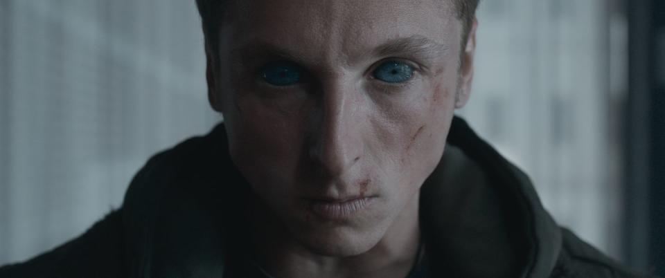 carlos scholz in awareness, a young man looks sternly at the camera with possessed eyes and scratches on his face