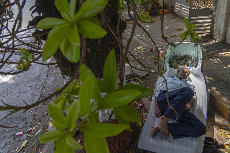 A laborer sleeps on a handcart in the shade of a tree during a hot summer day in Mumbai, India, Thursday, May 2, 2024. (AP Photo/Rafiq Maqbool)