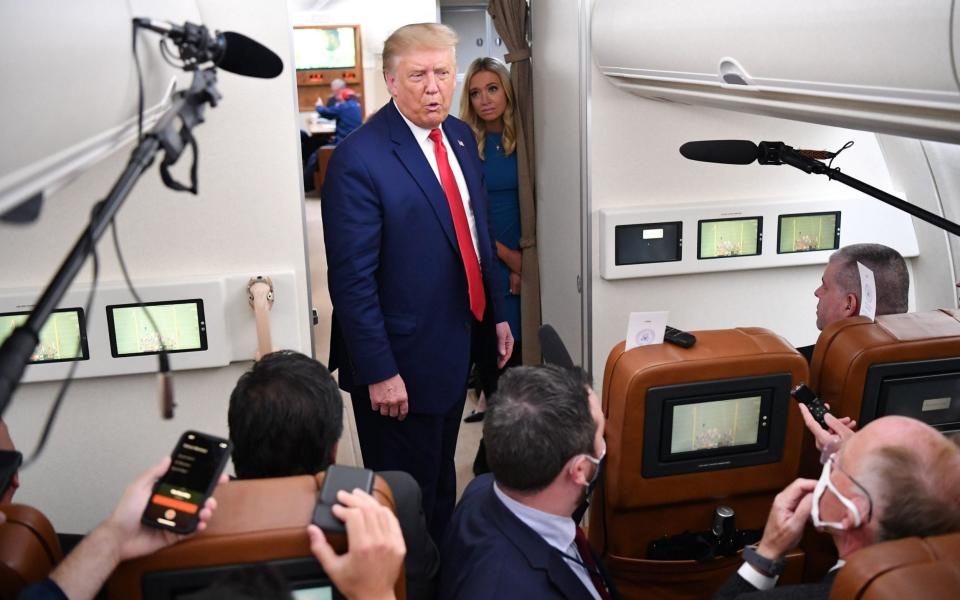 US President Donald Trump, flanked by White House Press Secretary Kayleigh McEnany, speaks to reporters onboard Air Force One - AFP