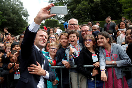 FILE PHOTO: French President Emmanuel Macron makes selfie with children during a ceremony marking the 78th anniversary of late French General Charles de Gaulle's resistance call of June 18, 1940, at the Mont Valerien memorial in Suresnes, near Paris, France, June 18, 2018. Picture taken June 18, 2018. REUTERS/Charles Platiau/Pool/File Photo