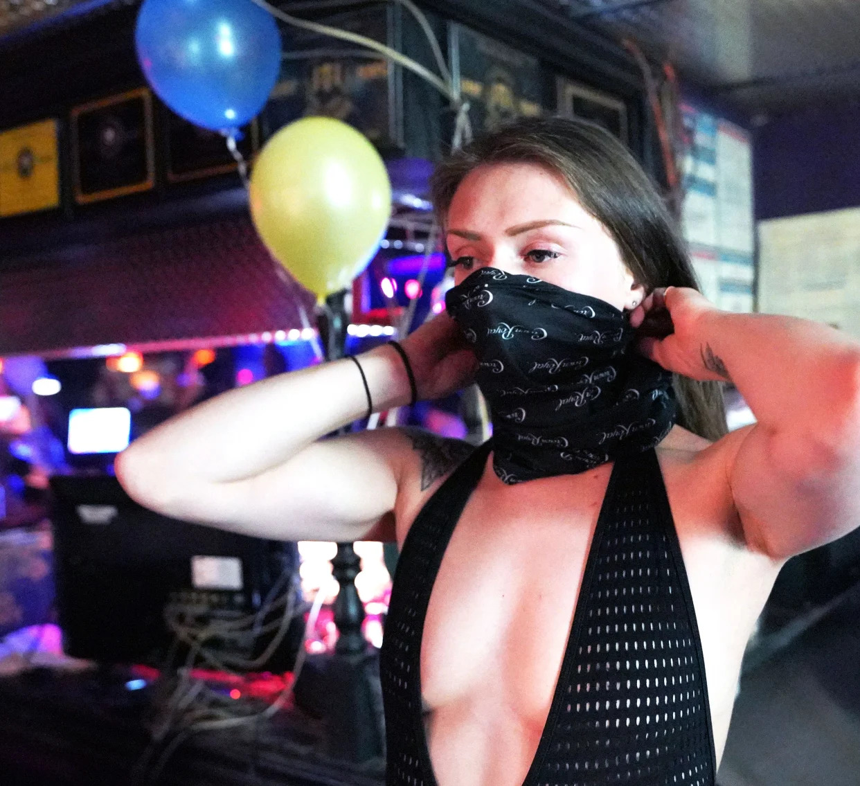 Boston, a dancer at The Den strip club in Cheyenne, Wyoming, tries on a new mask during the club's reopening Friday night. The club hosted a "masks on, clothes off" party to celebrate.