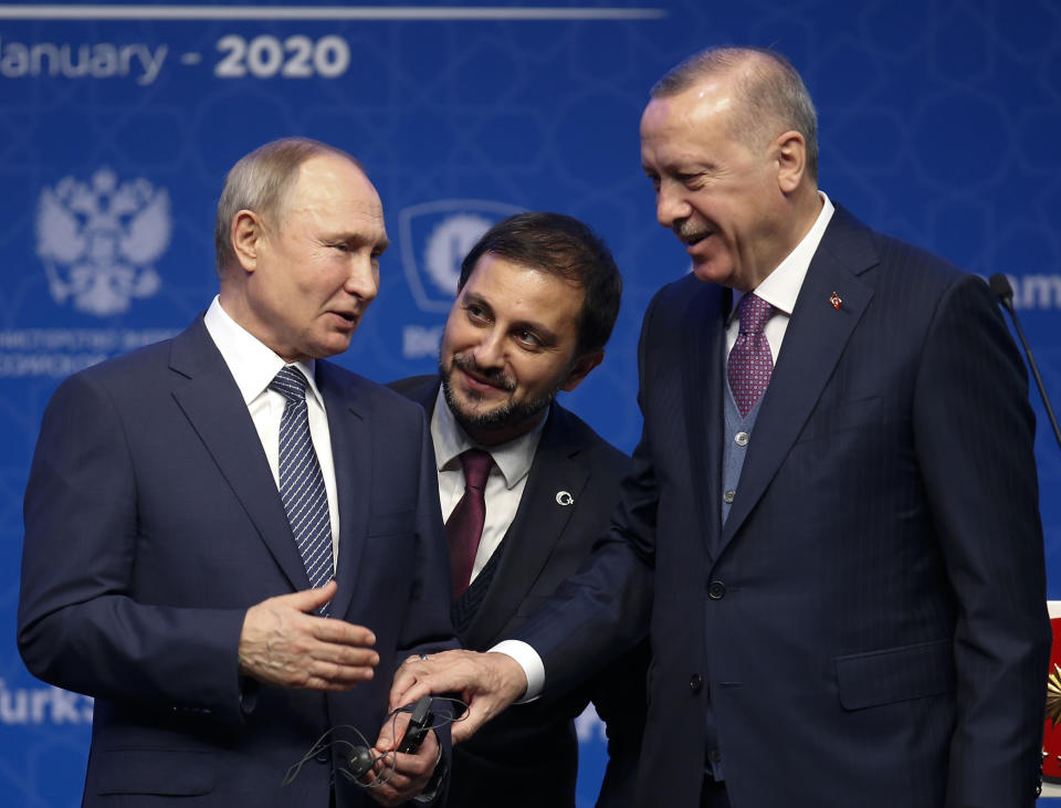 Turkey's President Recep Tayyip Erdogan, right and Russia's President Vladimir Putin, left, talk after they symbolically open a valve during a ceremony in Istanbul for the inauguration of the TurkStream pipeline, Wednesday, Jan. 8, 2020. Man in the centre is an interpreter.The dual natural gas line connecting the countries will open up a new export path for Russian gas into Turkey and Europe, through new and existing lines. (AP Photo/Lefteris Pitarakis)