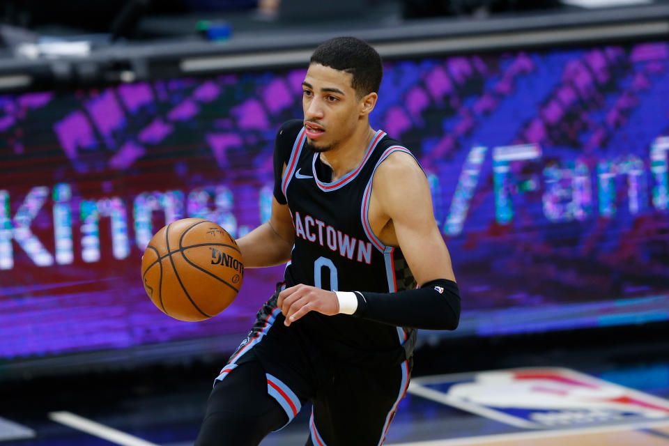 Tyrese Haliburton with the ball in one hand, wearing a black Sacramento Kings uniform.