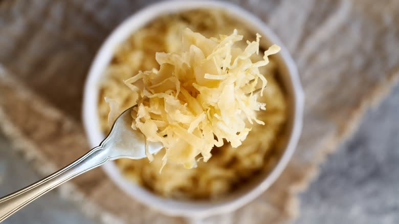 Fork holding sauerkraut over bowl