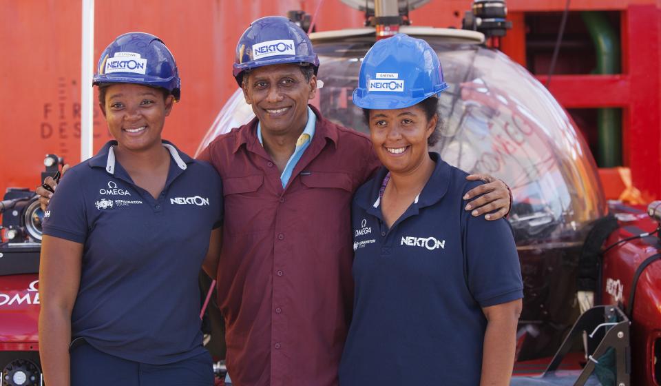 In this Saturday, April 13, 2019, photo, Seychelles President Danny Faure, center, smiles for a photograph with two young Seychellois scientists on board the Ocean Zephyr, off the coast of Desroches, in the outer islands of Seychelles. President Faure was visiting a British-led science expedition exploring the depths of the Indian Ocean where scientists documented changes taking place beneath the waves that could affect billions of people in the surrounding region over the coming decades. (AP Photo/Steve Barker)