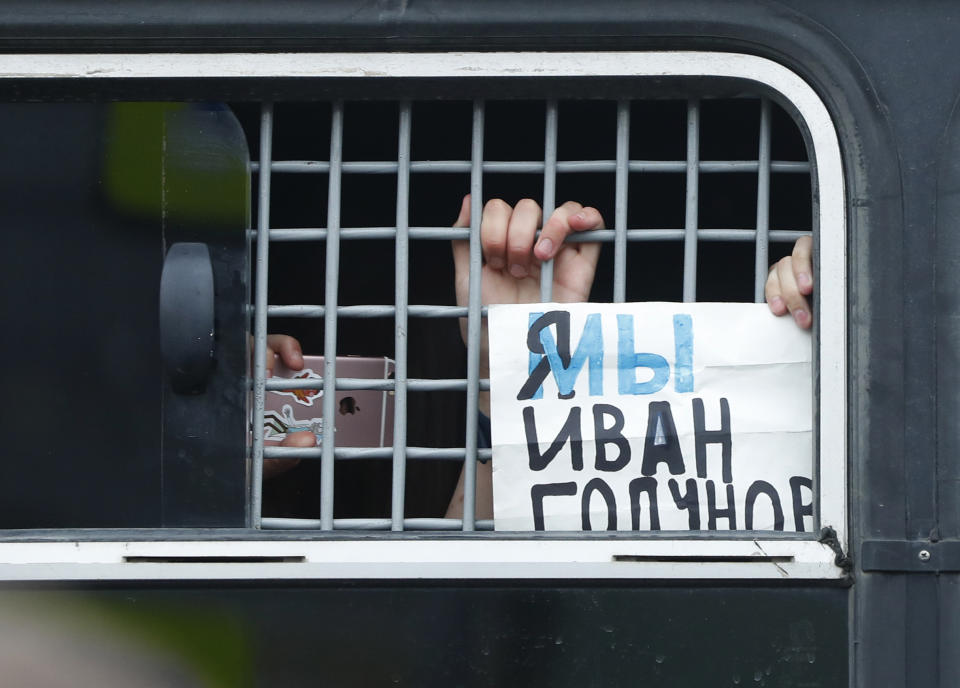 A detained supporter of Russian investigative journalist Ivan Golunov shows placard reading "I'm/we are Ivan Golunov" out of window of a police bus in Moscow, Russia, Wednesday, June 12, 2019. Police and hundreds of demonstrators are facing off in central Moscow at an unauthorized march against police abuse in the wake of the high-profile detention of a Russian journalist. More than 20 demonstrators have been detained, according to monitoring group.(AP Photo/Pavel Golovkin)