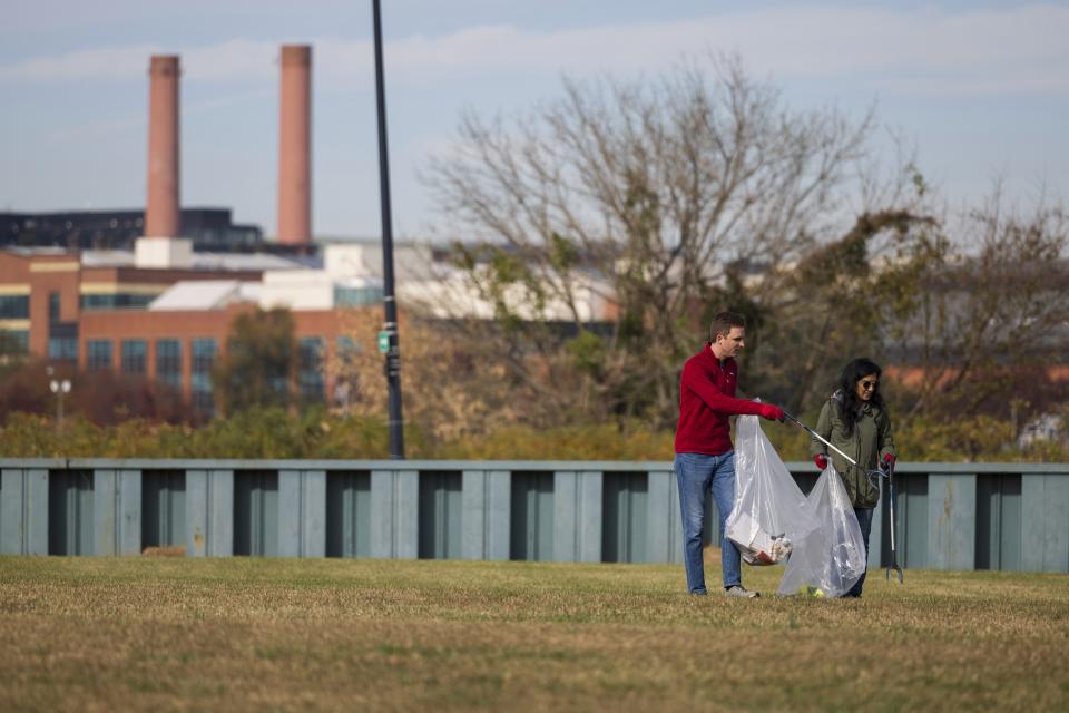 Volunteers collect trash items during a park cleanup on Wednesday, Nov. 15, 2023, at Anacostia Park in Washington. For decades, the Anacostia was treated as a municipal dumping ground for industrial waste, storm sewers and trash. A sewer upgrade in the city and decades of local environmental advocacy have brought improvements to the river, but change has come slowly. (AP Photo/Tom Brenner)