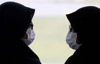 Two women wearing masks speak to each other at Kuala Lumpur International Airport in Sepang