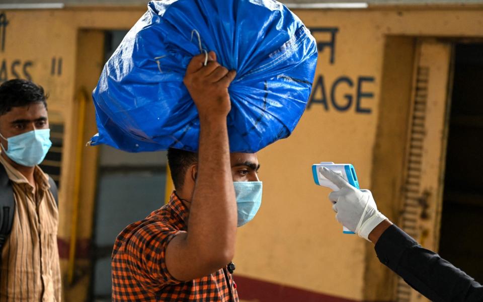 A passenger gets his temperature checked during a Covid-19 coronavirus screening after arriving at a railway platform on a long distance train - Punit PARANJPE / AFP