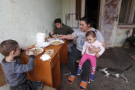 Members of the Hungarian Roma Bastyur family eat lunch outside their home in Bodvaszilas, Hungary, Monday, April 12,2021. Many students from Hungary's Roma minority do not have access to computers or the internet and are struggling to keep up with online education during the pandemic. Surveys show that less than half of Roma families in Hungary have cable and mobile internet and 13% have no internet at all. (AP Photo/Laszlo Balogh)