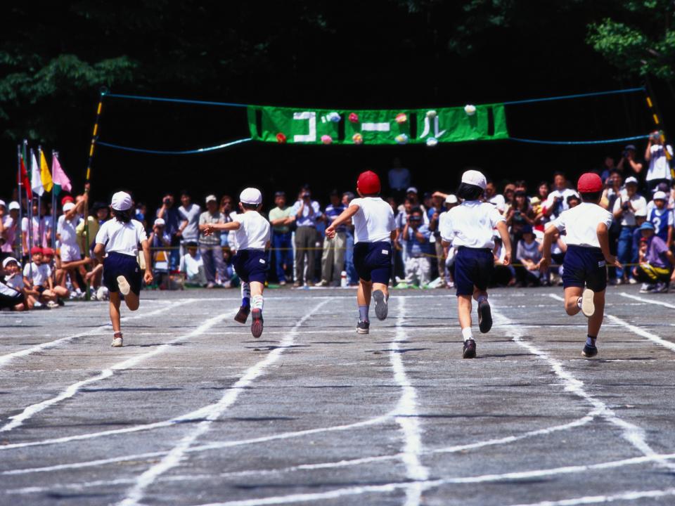 Five children running to the finish line in a school sports day.