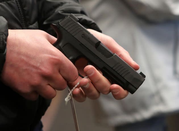 A man holds a Sig Sauer 9mm handgun at a Cheyenne, Wyoming, gun shop in March 2020. The Sig Sauer 9mm P938 is the focus of a lawsuit over a Georgia death.