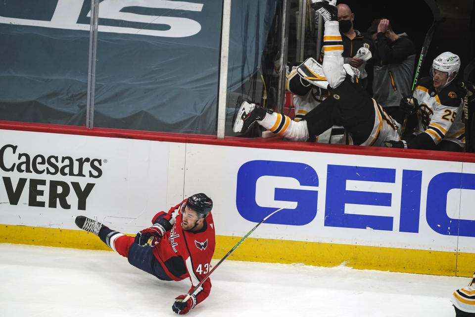 Washington Capitals right wing Tom Wilson (43) falls to the ice after checking Boston Bruins center Curtis Lazar (20) into his bench during the first period of Game 2 of an NHL hockey Stanley Cup first-round playoff series Monday, May 17, 2021, in Washington. (AP Photo/Alex Brandon)