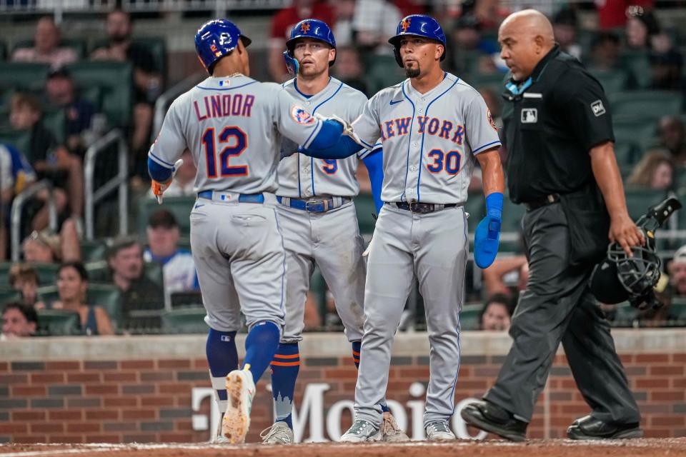 New York Mets shortstop Francisco Lindor (12) reacts with center fielder Brandon Nimmo (9) and center fielder Rafael Ortega (30) after hitting a three run home run against the Atlanta Braves during the sixth inning on Aug. 21, 2023, at Truist Park.