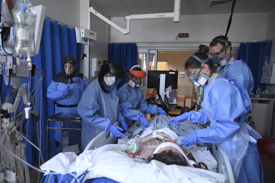 Members of the clinical staff wearing Personal Protective Equipment PPE care for a patient with coronavirus in the intensive care unit at the Royal Papworth Hospital in Cambridge, England, Tuesday May 5, 2020. (Neil Hall/Pool via AP)