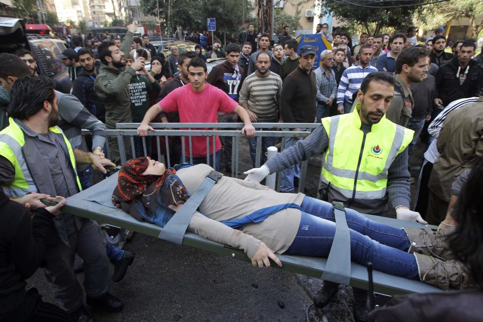 Civil defence personnel carry a wounded woman on a stretcher at the site of an explosion in the Haret Hreik area, in the southern suburbs of the Lebanese capital Beirut