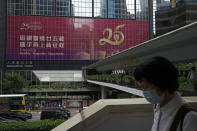 A woman walks past a banner to celebrate the 25th anniversary of Hong Kong handover to China, in Hong Kong, Wednesday, June 22, 2022. As the former British colony marks the 25th anniversary of its return to China, reeling from pandemic curbs that devastated business and a crackdown on its pro-democracy movement, Hong Kong leaders say it is time to transform again and become a tech center that relies more on ties with nearby Chinese factory cities than on global trade. (AP Photo/Kin Cheung)