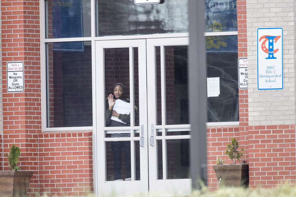 A student waits at the front entrance at Woodland Middle School in East Point, Ga.,Monday, March 9, 2020. The Fulton County School system has decided to close schools on Tuesday after a teacher tested positive with the coronavirus. The teacher was at Woodland Middle school on Friday. (Alyssa Pointer/Atlanta Journal-Constitution via AP)