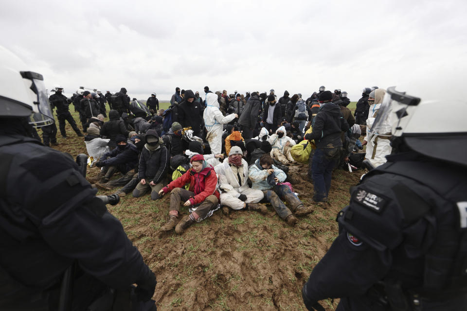 Police officers surround climate protesters sitting on the ground at the village Luetzerath near Erkelenz, Germany, Wednesday, Jan. 11, 2023. Police on Wednesday moved into a condemned village in western Germany, launching an effort to evict activists holed up at the site in an effort to prevent its demolition to make way for the expansion of a coal mine. (Rolf Vennenbernd/dpa via AP)