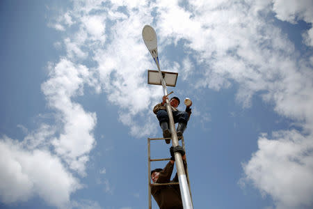 FILE PHOTO: A man paints a solar street lamp in the suburbs of Pyongyang, North Korea May 4, 2016. REUTERS/Damir Sagolj/File Photo