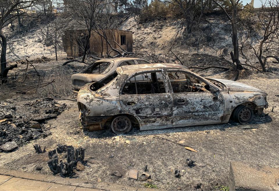 The gutted remains of cars lie on a road after a forest fire, on the island of Rhodes (AP)