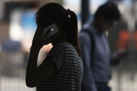 A woman speaks on her iPhone as she walks on a busy street in downtown Shanghai September 10, 2013. REUTERS/Aly Song/Files