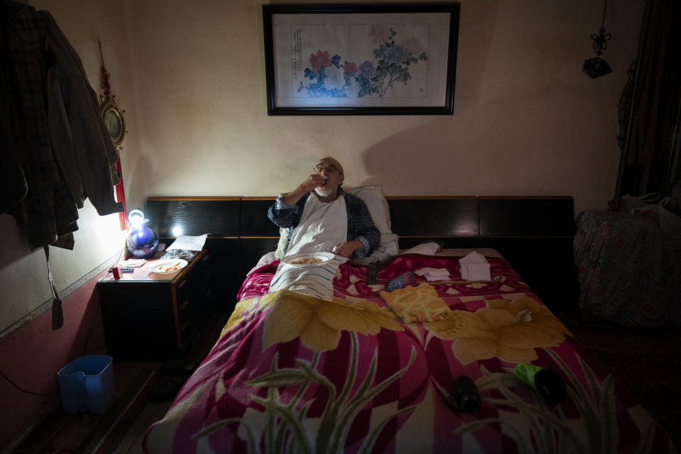 José Ribes Muñoz, watches television while eating his Christmas Eve dinner at his bed at his home in Barcelona, Spain, Thursday, Dec. 24, 2020. Ribes is used to being on his own since his wife left him. He kept the Spanish Christmas Eve tradition of eating prawns. He shelled and ate them propped up in the bed where he has all his meals and smokes the cigarettes that give his home the permanent smell of stale tobacco. (AP Photo/Emilio Morenatti)