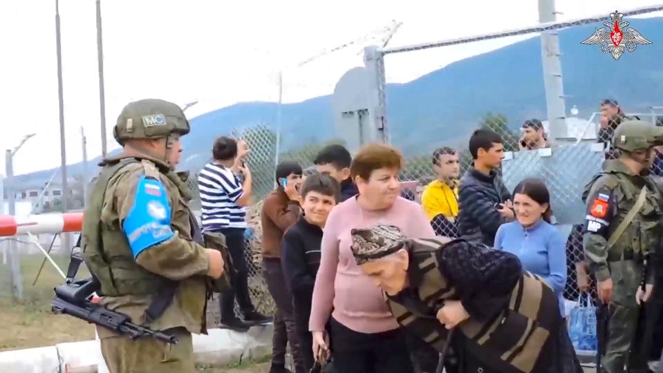 In this photo taken from video released by Russian Defense Ministry Press Service on Thursday, Sept. 21, 2023, Russian peacekeepers guard a gate into a camp near Stepanakert in Nagorno-Karabakh. Thousands of Nagorno-Karabakh residents flocked to a camp operated by Russian peacekeepers to avoid the fighting, while many others gathered at the airport of the regional capital, Stepanakert, hoping to flee the region. (Russian Defense Ministry Press Service via AP)