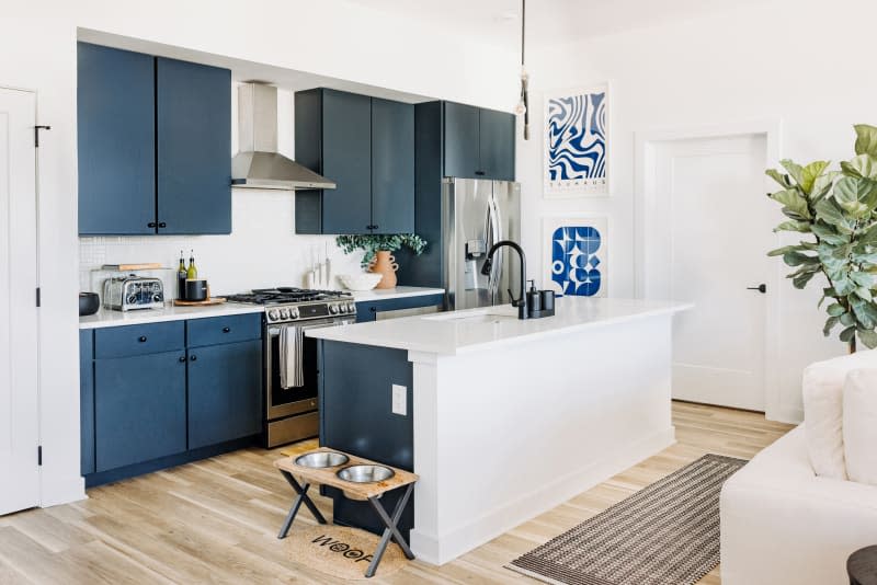 White kitchen with blue cabinets and blue and white art