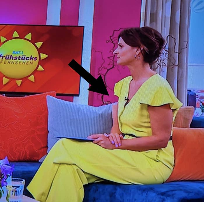 A woman in a jumpsuit sits on a couch in a TV studio for SAT.1 Frühstücksfernsehen