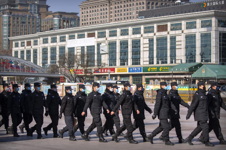 Policemen wear face masks as they march in formation outside the Beijing Railway Station in Beijing, Saturday, Feb. 15, 2020. People returning to Beijing will now have to isolate themselves either at home or in a concentrated area for medical observation, said a notice from the Chinese capital's prevention and control work group published by state media late Friday. (AP Photo/Mark Schiefelbein)