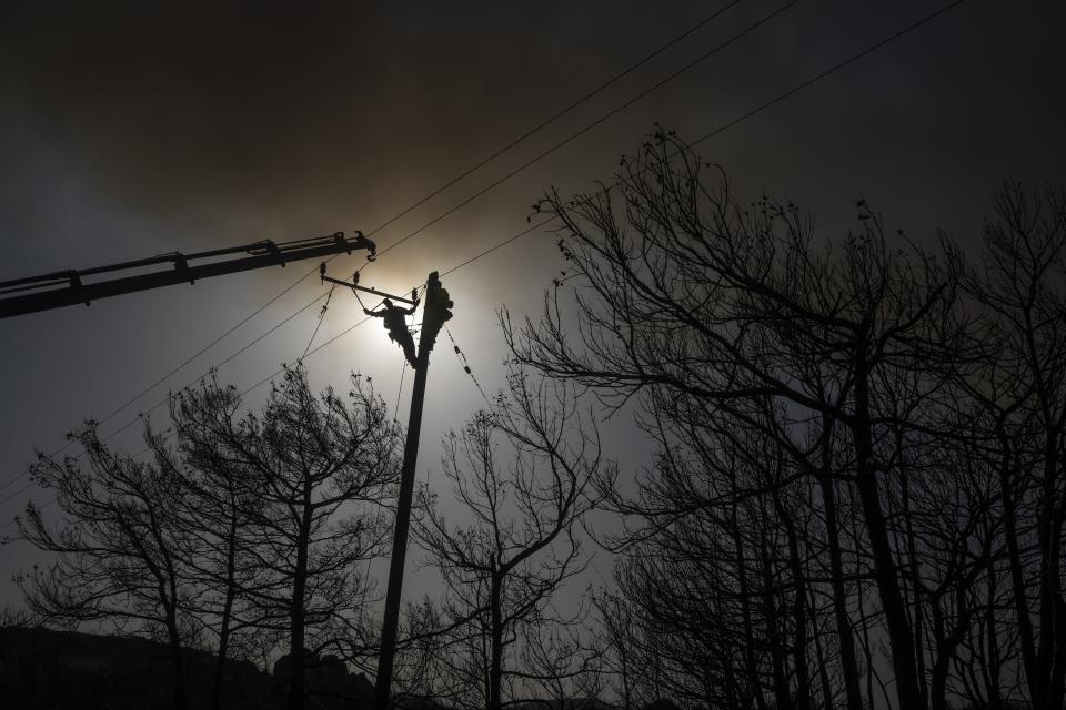 A worker climbing on an electricity pole repairs cables after a wildfire near Gennadi village, on the Aegean Sea island of Rhodes, southeastern Greece, on Wednesday, July 26, 2023. Major fires raging in Greece and other European countries have advanced. The flames have caused additional deaths, destroying homes and threatening nature reserves during a third successive wave of extreme temperatures. (AP Photo/Petros Giannakouris)