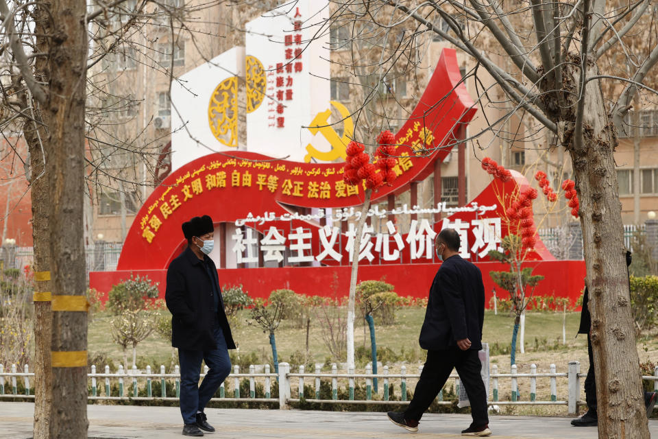 Residents walk past government propaganda, some of which reads, "Socialist core values," in Hotan in northwestern China's Xinjiang Uyghur Autonomous Region on March 22, 2021. Four years after Beijing's brutal crackdown on largely Muslim minorities native to Xinjiang, Chinese authorities are dialing back the region's high-tech police state and stepping up tourism. But even as a sense of normality returns, fear remains, hidden but pervasive. (AP Photo/Ng Han Guan)