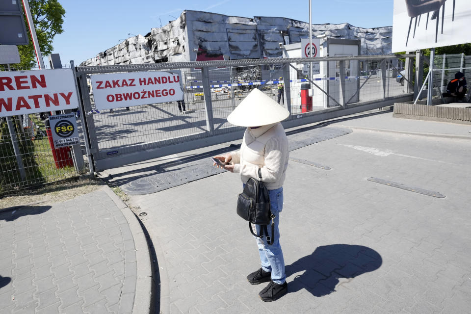 A member of Poland's Vietnamese community checks her phone in Warsaw, Poland, Wednesday, May 15, 2024, outside a shopping center destroyed in a weekend fire. A weekend fire in a shopping center in Warsaw dealt tragedy to many members of Poland's Vietnamese community. People lost entire livelihoods and say they don't know how they will manage to make a living. (AP Photo/Czarek Sokolowski)
