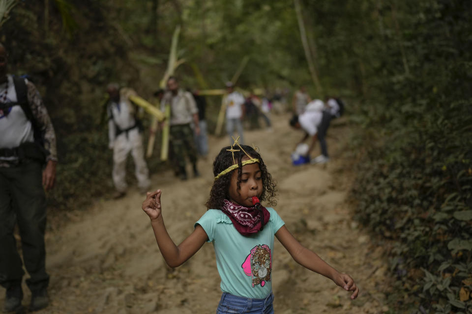 A girl blows a whistle as she descends the Cerro el Avila with members of the Palmeros de Chacao brotherhood, in Caracas, Venezuela, Saturday, April 1, 2023. Every year the brothers climb the Cerro El Avila to collect royal palm branches as part of a 250-year tradition that marks the start of Holy Week. The palms will be blessed at the Palm Sunday Mass in the Chacao church. (AP Photo/Matias Delacroix)