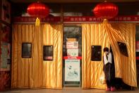 A woman wearing a face mask leaves a supermarket decorated with Chinese New Year lanterns in Beijing