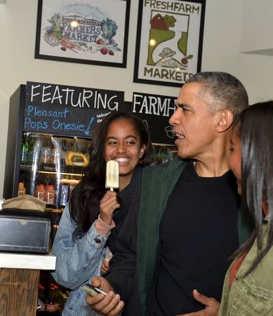 U.S. President Barack Obama (C) chats with workers at Pleasant Pops next to his daughters Sasha (R) and Malia, who is enjoying a popsicle, in Washington, November 28, 2015. REUTERS/Mike Theiler